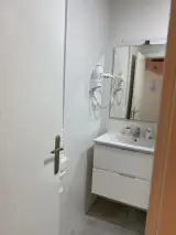 Vista cercana del baño con secador de pelo de pared y espejo junto al lavabo de la habitación